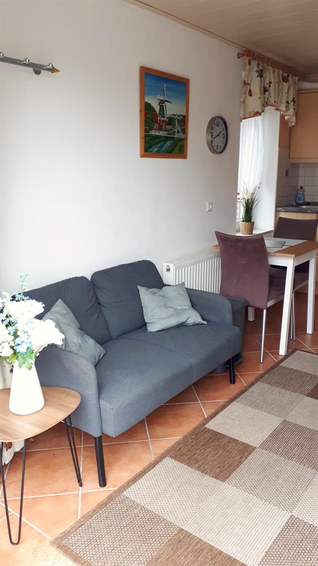 Wohnbereich mit grauem Sofa, Beistelltisch und Esstisch am Fenster